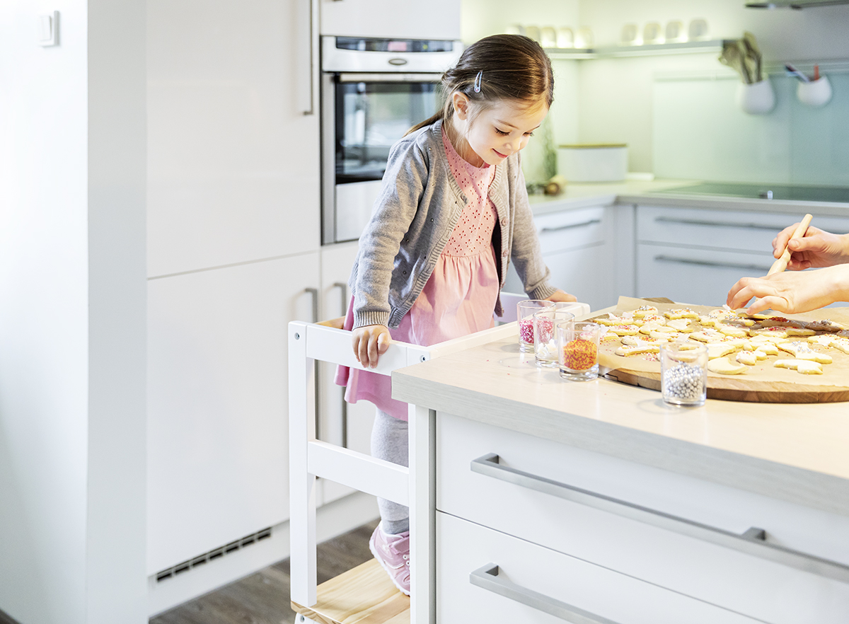 Mädchen auf BOMI Lernturm beim gemeinsamen Backen in der Küche